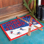 Doormat with 'Gone Skiing' text and skiing graphics on a wooden floor.