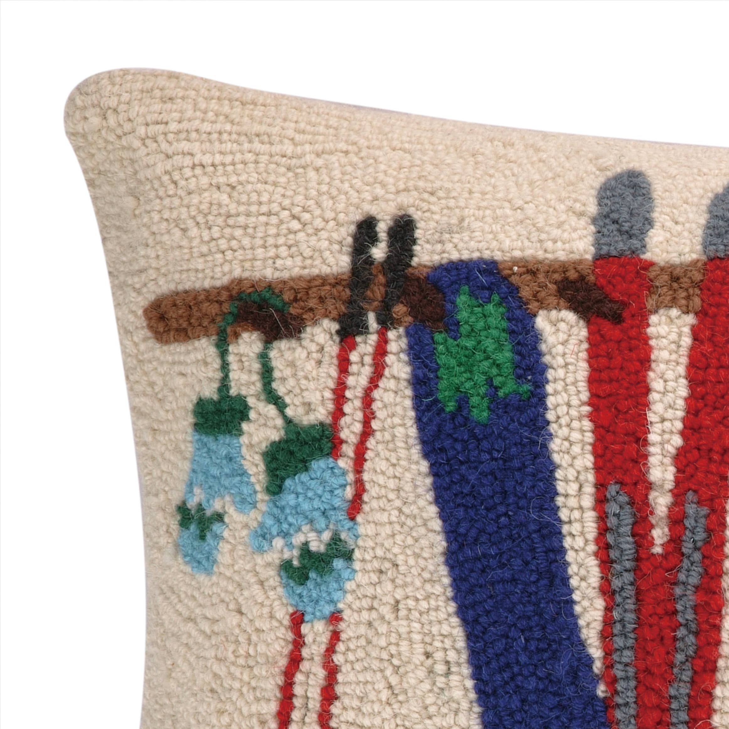 Close up of decorative pillow with embroidered design of clothes on a line against a white background