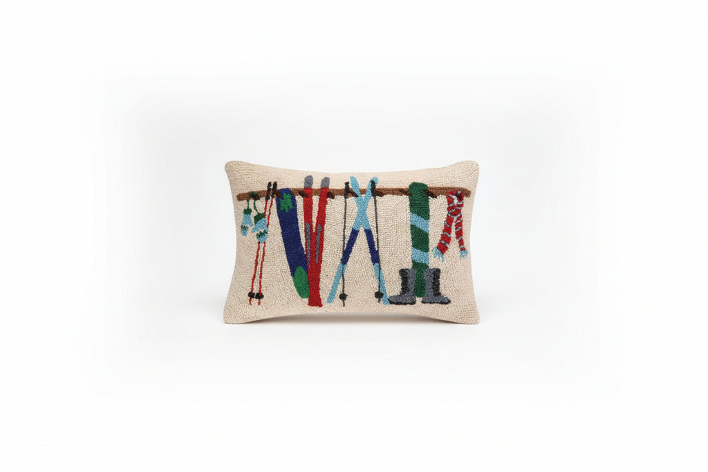 Decorative pillow with skis and boots on a wooden ski rack against a beige background